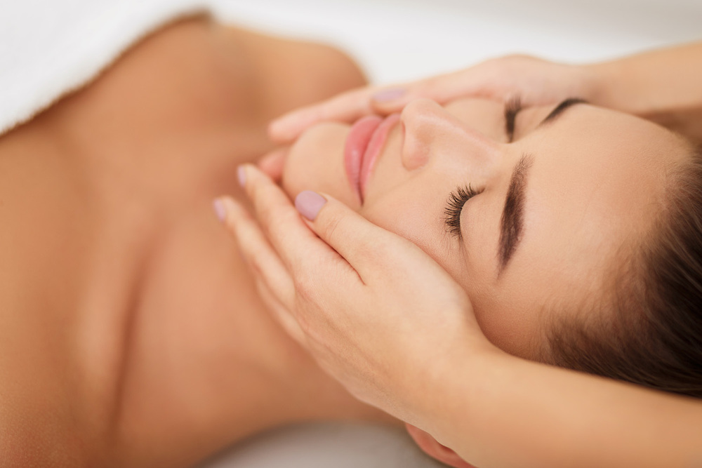 Facial beauty treatment. Woman getting face massage at beauty salon, closeup